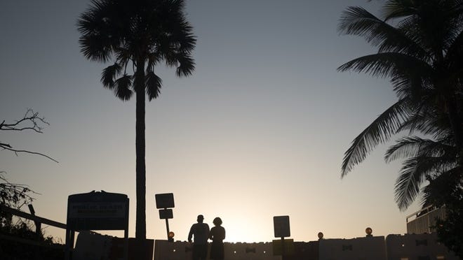 Lantana residents Burt Garnsey, 48, left, and Gage Garnsey, 18, study the Lantana Beach in Lantana at sunrise. (Andres Leiva / The Palm Beach Post)