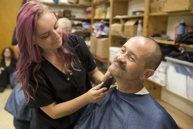 Ariana Ward gives Brian Werner a shave and a haircut at the Homeless Vet Stand Down at First Baptist Church in Panama City on Thursday. Ward and dozens of students from Haney's cosmetology school gave free haircuts during the event. [JOSHUA BOUCHER/THE NEWS HERALD]