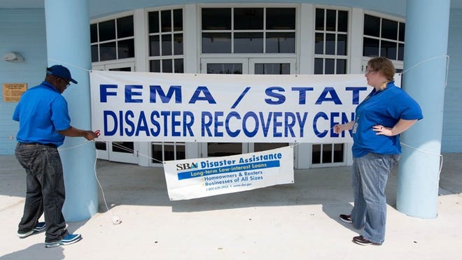 Martins Nnoko and Andi Wilson, with the SBA Disaster Assistance set up their sign at the FEMA/State Disaster Recovery Center that has opened at the Carolyn Sims Center, 225 NW 12th. Avenue in Boynton Beach. (Allen Eyestone / The Palm Beach Post)