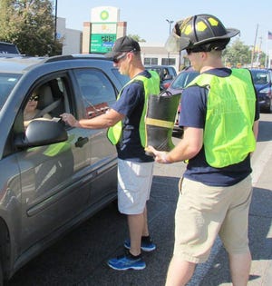 Drive-thru donation Captain Landon Horrie and firefighter Zack Clark give motorists the boot on Main Street Friday as part of the Kewanee Fire Dept.'s annual MDA drive.