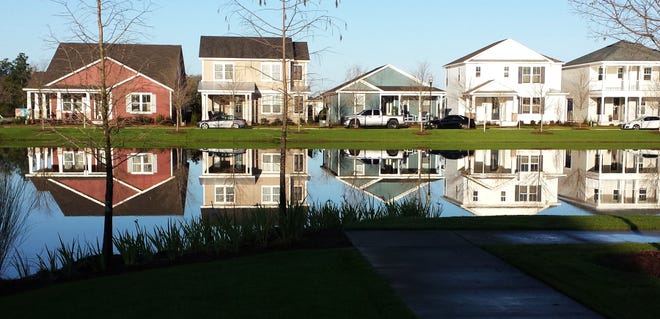 Homes are reflected from the water in SweetBay, which recently marked its 100th home sale. [RAY GLENN/NEWS HERALD]
