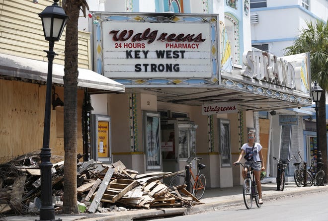 A cyclist rides past a pile of debris Thursday in Key West. Businesses and residents in the Keys are removing debris and fixing damage caused by Hurricane Irma in anticipation of the return of tourists in the area. [WILFREDO LEE/AP]