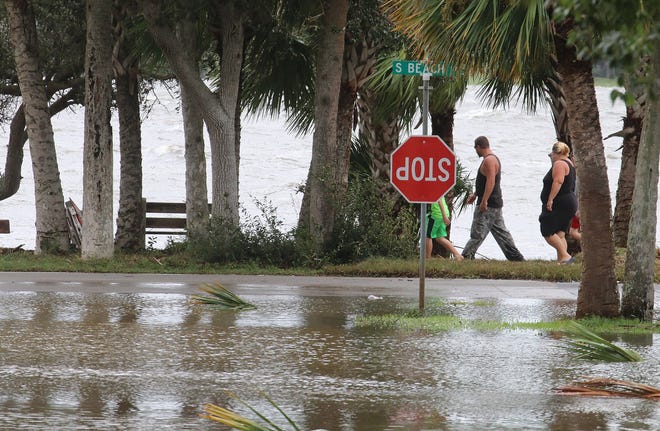 People walk along a flooded Beach Street south of the Granada Bridge in Ormond Beach as the aftermath of Hurricane Irma becomes clear Monday morning, Sept. 11, 2017. Workers at many local businesses impacted by flooding will face challenges in the coming weeks. [News-Journal/Jim Tiller]
