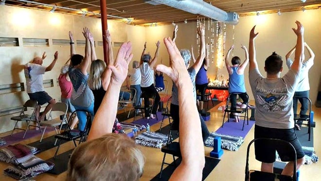 Cancer patients, survivors and caregivers strike a tree pose at a yoga4cancer class at Dragonfly Yoga Studio in Fort Walton Beach. [SPECIAL TO THE DAILY NEWS]