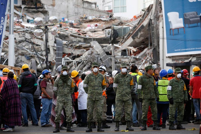 Rescue workers and volunteers stand in the middle of the street after an earthquake alarm sounded and a small tremor was felt during rescue operations at the site of a collapsed building in Roma Norte, in Mexico City, Saturday, Sept. 23, 2017. All rescue workers atop the rubble were able to evacuate safely via an adjacent building. (AP Photo/Rebecca Blackwell)