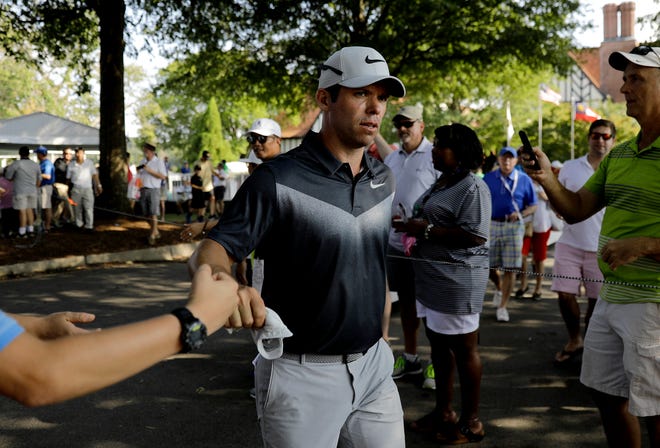 Paul Casey fist-bumps spectators as he walks off the ninth hole during the third round of the Tour Championship on Saturday. Casey carded a 5-under 65 to take a two-stroke lead. [AP Photo/David Goldman]