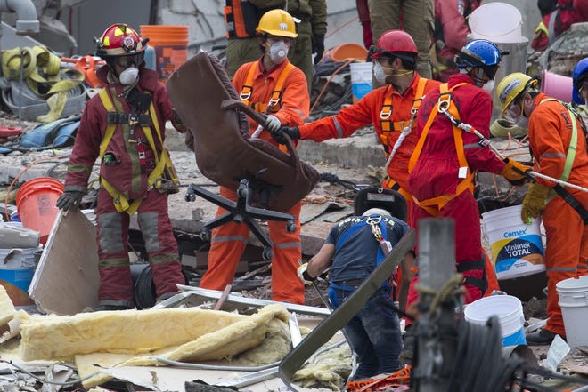 A rescue worker removes a chair found at a search and rescue site of a felled office building brought down by a 7.1-magnitude earthquake Saturday in Mexico City. [MOISES CASTILLO/AP]