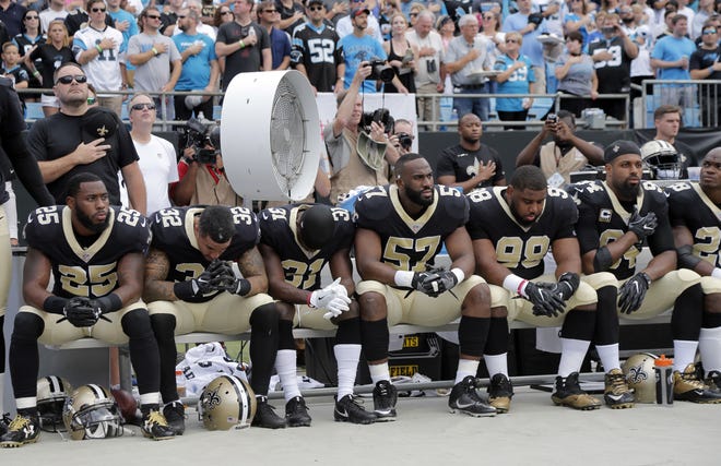 New Orleans Saints players sit on the bench during the national anthem before an NFL football game against the Carolina Panthers in Charlotte, N.C., Sunday, Sept. 24, 2017. (AP Photo/Bob Leverone)