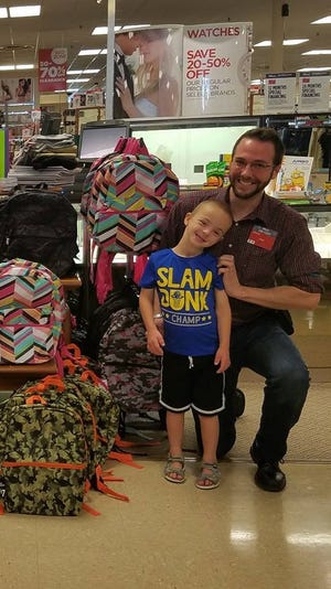 Lucas Bibeau, a local 7-year-old boy with Down syndrome, poses with Rochester JCPenney General Manager Jon Herrick after raising more than 130 backpacks for area students with special needs during a recent charity effort through the nonprofit Lucas' Helping Hands. [Courtesy photo]