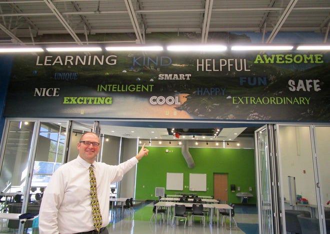 Northside principal Alex Kashner points to the words on the wall between the school cafeteria and collaboration room. The words were submitted by students and staff when asked ‘what word describes Northside,’ and then incorporated into the 
interior décor of the new addition to the school.