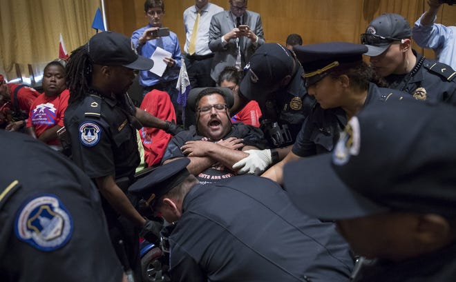 Activists opposed to the GOP's Graham-Cassidy health care repeal bill, many with disabilities, are removed Monday by U.S. Capitol Police after disrupting a Senate Finance Committee hearing on the last-ditch GOP push to overhaul the nation's health care system. [AP Photo/J. Scott Applewhite]