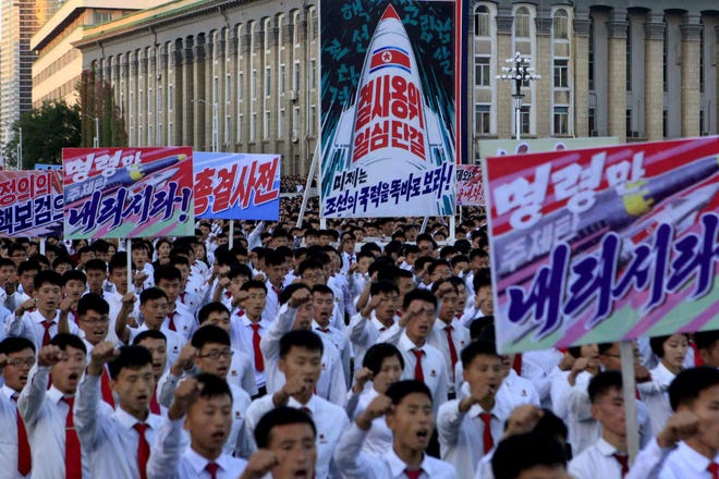North Koreans gather at Kim Il Sung Square to attend a mass rally against America on Saturday in Pyongyang, North Korea. Seen on the sign with the painting of a rocket in the center are Korean words which read "defend until the death, single hearted unity" and below it in blue "the American imperialists should see clearly the power of our country," the sign in the foreground right reads "please give us the order." [AP Photo/Jon Chol Jin]