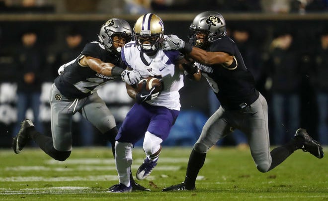 Washington wide receiver Chico McClatcher, center, is stopped by Colorado defensive backs Isaiah Oliver and Evan Worthington, right, during the first half of an NCAA college football game Saturday, Sept. 23, 2017, in Boulder, Colo. (AP Photo/David Zalubowski)