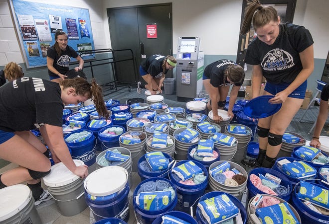 In this Sept. 25, 2017, photo, members of the community join the Eastern Mennonite University volleyball team as they pack buckets with relief kits bound for hurricane-ravaged Puerto Rico in Harrisonburg, Va. (Daniel Lin/Daily News-Record via AP)