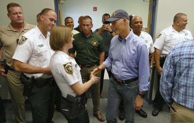 Florida Gov. Rick Scott, right, thanks members of the Hillsborough County Sheriff's Office for their service before a press conference at the Falkenburg Road facility in Tampa Tuesday, Sept. 19, 2017. (James Borchuck/The Tampa Bay Times via AP)