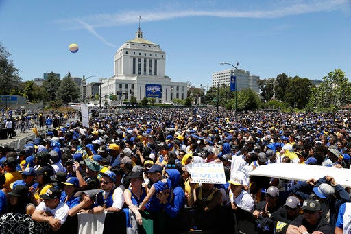 FILE - In this June 15, 2017 file photo, people fill a plaza at the Henry J. Kaiser Convention Center to watch the Golden State Warriors' NBA championship rally in Oakland, Calif. Oakland officials say the Golden State Warriors made good on their word and have refunded the city almost $800,000 spent to host the team's 2017 Championship parade. (AP Photo/Eric Risberg, File)