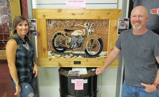 Bethan and Tommy Hamilton of Hamilton Harley-Davidson display stained-glass artwork created by Ann Scott. The art will be auctioned Saturday at a poker run to benefit breast cancer awareness.