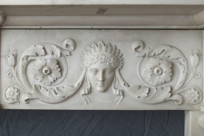 A detail of the mantlepiece lintel with a carved with classical goddesses.