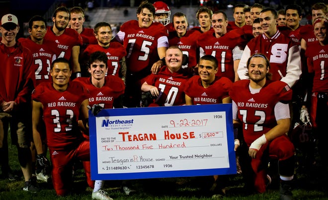 Senior honorary captain Teagan House, center, is surrounded by Spaulding football teammates after he was presented a check for $2,500 before last week's Division I game with Bedford. [Shawn St. Hilaire/Fosters.com]