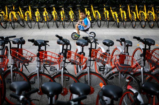 FILE - In this Aug. 31, 2017 file photo, a child rides past bicycles from bike-sharing companies parked along a sidewalk in Beijing. A report says China’s factory activity expanded in September at the fastest pace in five years, indicating a healthy outlook for the world’s second-biggest economy. (AP Photo/Andy Wong, File)