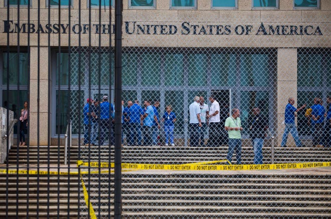 Staff stand within the United States embassy facility in Havana, Cuba, Friday, Sept. 29, 2017. The United States issued an ominous warning to Americans on Friday to stay away from Cuba and ordered home more than half the U.S. diplomatic corps, acknowledging neither the Cubans nor America’s FBI can figure out who or what is responsible for months of mysterious health ailments. (AP Photo/Desmond Boylan)