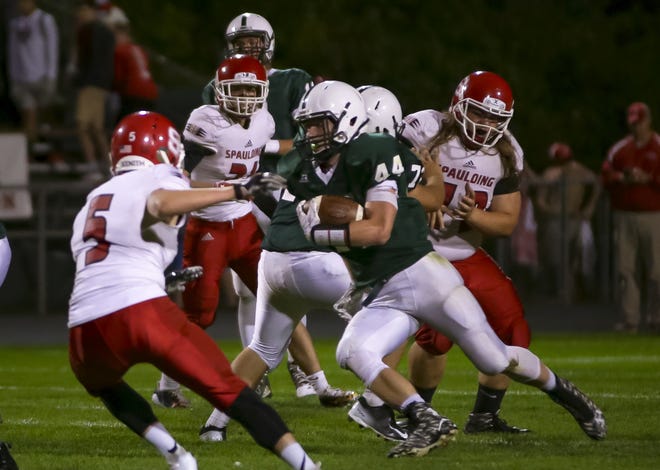Dover's Devin Cady, center, powers his way past Spaulding's Noah McCann (5) during Friday night's Division I game at Dunaway field. [Shawn St. Hilaire/Fosters.com]