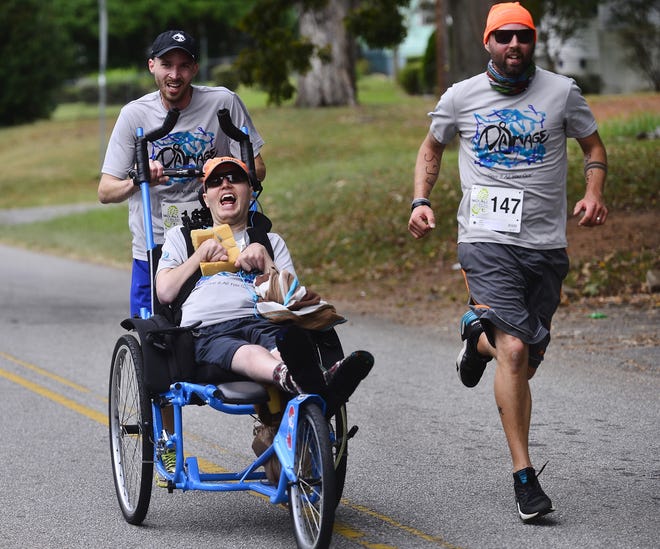 Jeremy Vangsnes is pushed by his brother Brett as another brother, Travis, runs at their side during the Walk a Mile in Their Shoes 5K at Duncan Park on Saturday. [ALEX HICKS JR./Spartanburg Herald-Journal]