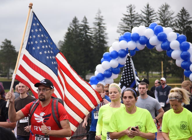 A man proudly totes an American flag as he runs in the Cpl. Bryon Dickson Memorial 5k at East Stroudsburg University on Saturday, Sept. 30, 2017. (PATRICK CAMPBELL/POCONO RECORD)