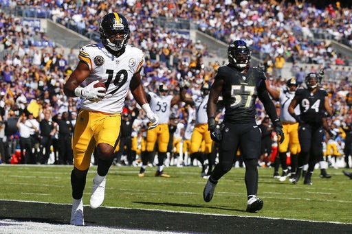 Pittsburgh Steelers wide receiver JuJu Smith-Schuster (19) carries the ball into the end zone for a touchdown as Baltimore Ravens inside linebacker C.J. Mosley (57) watches during the first half in Baltimore, Sunday.
