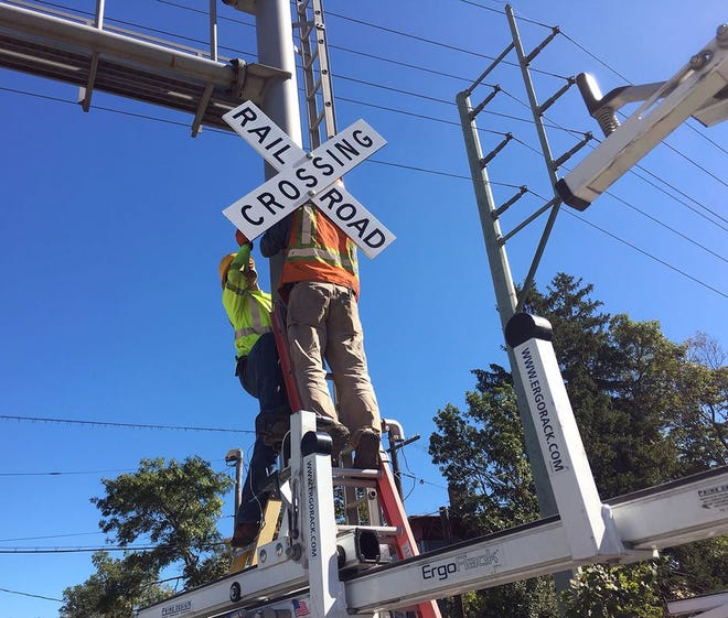 A Mass Coastal Railroad worker attaches a new railroad crossing sign to the recently upgraded crossing on Winthrop Street in Taunton.