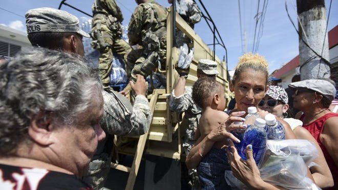 In this Sept. 24, 2017, photo, National Guard Soldiers arrive at Barrio Obrero in Santurce to distribute water and food among those affected by the passage of Hurricane Maria, in San Juan, Puerto Rico. Federal aid is racing to stem a growing humanitarian crisis in towns left without fresh water, fuel, electricity or phone service by the hurricane. (AP Photo/Carlos Giusti)