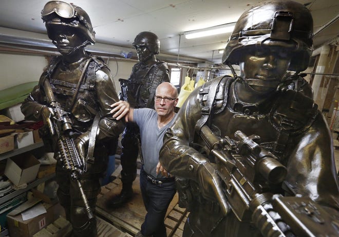 Alan Cottrill, a well-known Zanesville, Ohio sculptor, was commissioned by the National Infantry Museum in Georgia to do nine 7-foot sculptures of combat soldiers for the Global War on Terror Memorial. Cottrill stands in his studio with some of the finished statues on Thursday, Sept. 21, 2017. [Fred Squillante/The Columbus Dispatch via AP]