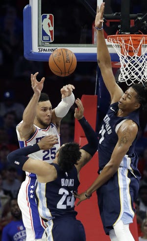 The 76ers' Ben Simmons (25) passes the ball as the Grizzlies' Dillon Brooks (24) and Deyonta Davis (21) defend during Wednesday's NBA preseason opener.