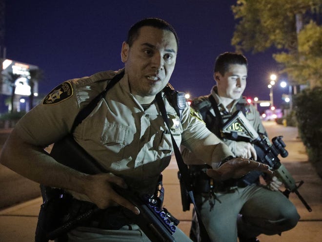 Police officers advise people to take cover near the scene of a shooting near the Mandalay Bay resort and casino on the Las Vegas Strip, Sunday, Oct. 1, 2017, in Las Vegas. (AP Photo/John Locher)