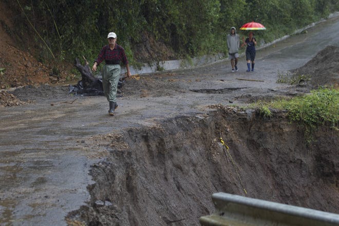 Neighbors walk under the rain past a washed out road in Alajuelita on the outskirts of San Jose, Costa Rica, Thursday. Tropical Storm Nate formed off the coast of Nicaragua on Thursday and was being blamed for deaths in Central America as it spun north toward a potential landfall on the U.S. Gulf Coast as a hurricane over the weekend. (AP Photo/Moises Castillo)