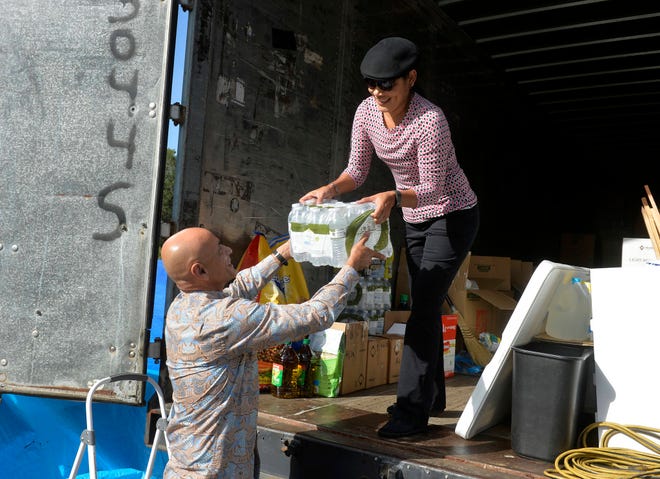 Frank Ruiz, pastor of the Spanish speaking ministry at the Sanctuary on Whitfield Avenue, hands bottled water to his wife Karla to store in a container bound for Puerto Rico. (Steve Bisson/Savannah Morning News)