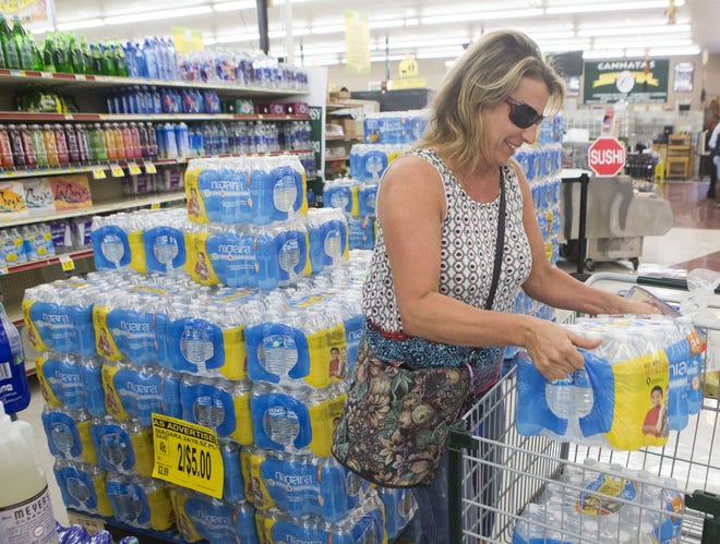Darlene Naquin loads bottled water into a shopping cart Friday morning at Cannata's supermarket on West Park Avenue in Houma. [Chris Heller/Staff -- houmatoday/dailycomet]