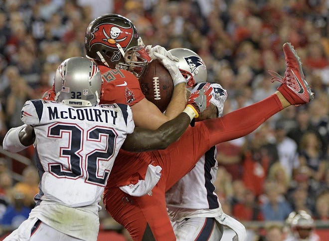 Tampa Bay Buccaneers tight end Cameron Brate (84) pulls in an 18-yard touchdown pass in front of New England Patriots free safety Devin McCourty (32) and strong safety Patrick Chung during the fourth quarter of an NFL football game Thursday, Oct. 5, 2017, in Tampa, Fla. (AP Photo/Phelan Ebenhack)