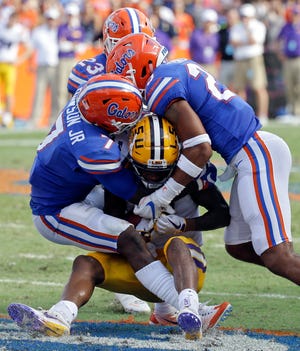 LSU's D.J. Chark, center, is stopped by Florida's Duke Dawson (7), Chauncey Gardner Jr. (23) and Jeawon Taylor during the first half Saturday in Gainesville. [Associated Press/John Raoux]
