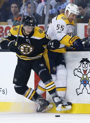 The Bruins' Sean Kuraly, left, checks the Predators' Cody McLeod during Thursday's opener in Boston. [Michael Dwyer/AP]