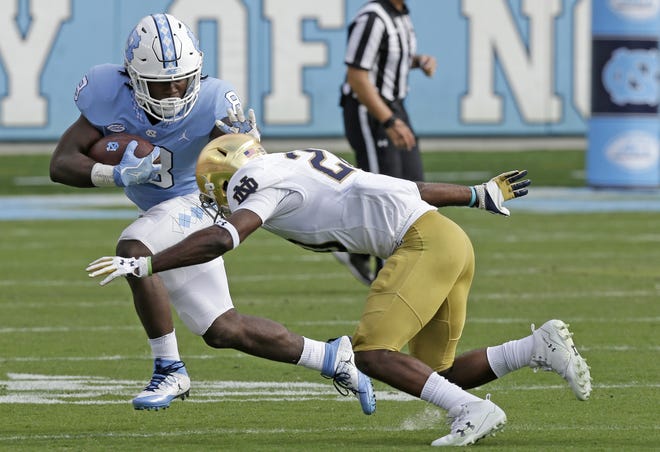 North Carolina's Michael Carter (8) runs while Notre Dame's Shaun Crawford looks to tackle him during the first half of an NCAA college football game in Chapel Hill, N.C., Saturday, Oct. 7, 2017. (AP Photo/Gerry Broome)