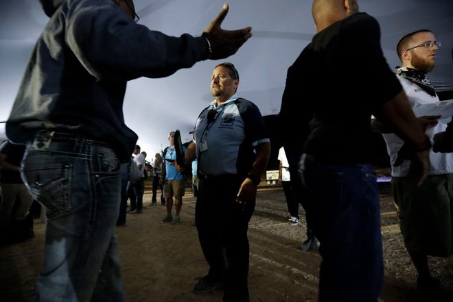 Security guard Jose Sanchez checks concert goers on his first day back at a large event since he worked during last Sunday's mass shooting Friday, Oct. 6, 2017, on the outskirts of Las Vegas. Sanchez and his colleagues at a private security firm manning the Route 91 Harvest music festival Sunday night in Las Vegas were a force of 200 unarmed first responders who helped people exit amid the panic. Despite the fresh trauma and losing one of their own, many of the company's guards are returning to work events for the first time again this weekend. [AP Photo/Gregory Bull]