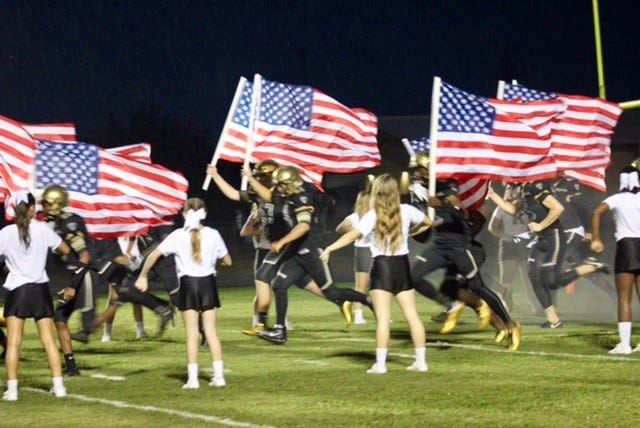 East Ridge football players charge onto the field with flags to pay tribute to the U.S. military. [SUBMITTED]