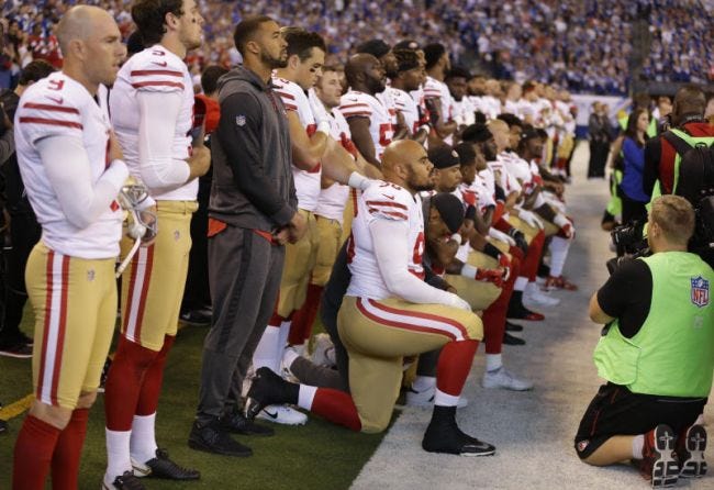 Members of the San Francisco 49ers kneel during the playing of the national anthem before their game Sunday in Indianapolis against the Colts.