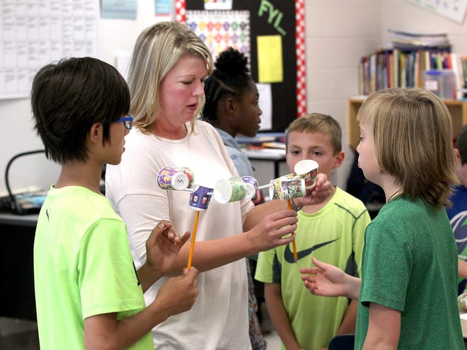 Lowell Elementary fifth grade teacher Allison Miller checks students' work on the anemometers that they were making in class Thursday afternoon. Miller is one of the fourth and fifth grade teachers across the state that would be eligible for a proposed bonus based on students' end-of-grade test scores. [JOHN CLARK/THE GASTON GAZETTE]