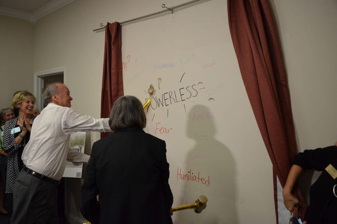 Wayne (left) and Delores Barr Weaver symbolically began the renovation of the Women’s Center’s new Sexual Assault Forensic Exam Center at a Tuesday night fundraiser, smashing holes in a wall of what will be the reception area as they aimed at words written there by staff that depict what they don’t want victims to feel there, like powerless and fear. (Dan Scanlan/Florida Times-Union)