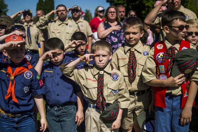 Boy Scouts and Cub Scouts salute during a Memorial Day ceremony in Linden, Mich. On Wednesday, Oct. 11, 2017, the Boy Scouts of America Board of Directors unanimously approved to welcome girls into its Cub Scout program and to deliver a Scouting program for older girls that will enable them to advance and earn the highest rank of Eagle Scout. (Jake May/The Flint Journal - MLive.com via AP)