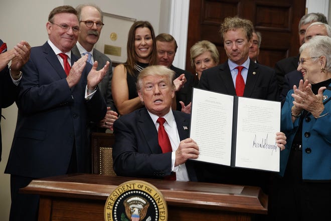 President Donald Trump shows an executive order on health care that he signed in the Roosevelt Room of the White House, Thursday, Oct. 12, 2017, in Washington. (AP Photo/Evan Vucci)