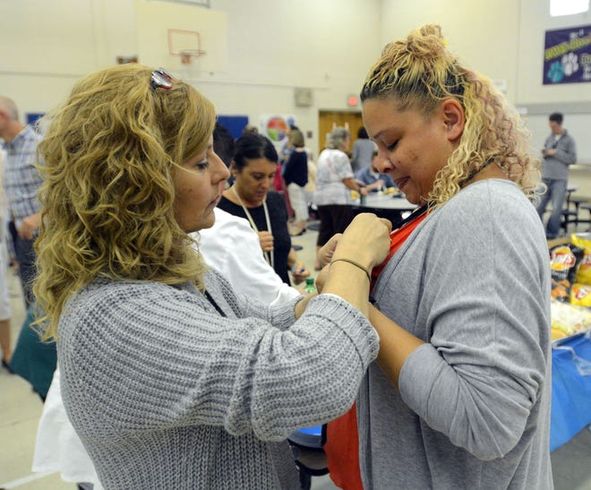 Joyce Klaver, left, pins a blue ribbon onto Arelis Aliceas during a luncheon Thursday for the staff at theThomas W. Mahan School to celebrate their Blue Ribbon Award. Both are para-educators at the school. [Aaron Flaum/NorwichBulletin.com]