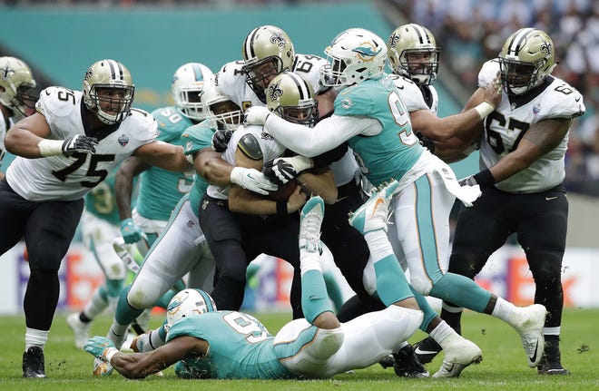 New Orleans Saints quarterback Drew Brees, center, is sacked by the Miami Dolphins defense during the first half of a game on Oct. 1 at Wembley Stadium in London. The Dolphins' offense ranks as the NFL's worst, and their defense is among the best, but players say there's no friction between the two units. [AP Photo / Matt Dunham, File]